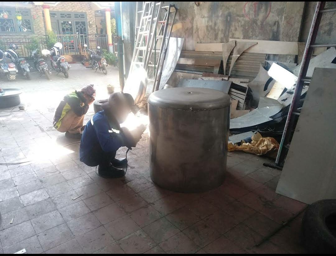 Teknisi mengelas komponen mesin di workshop
